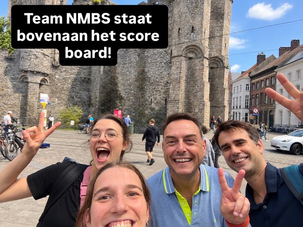 Vier spelers maken een selfie voor het Gravensteen in Gent, met over het beeld de tekst: team NMBS staat bovenaan het scorebord