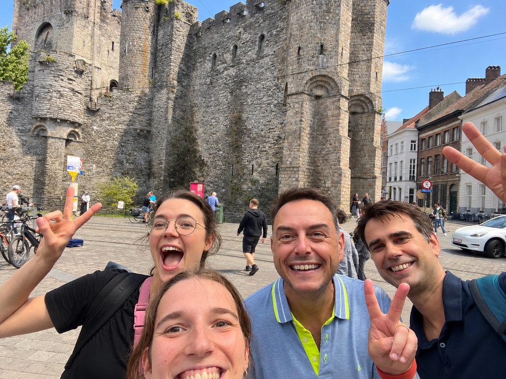 Vijf spelers lachen en steken hun hand op voor het Gravensteen in Gent
